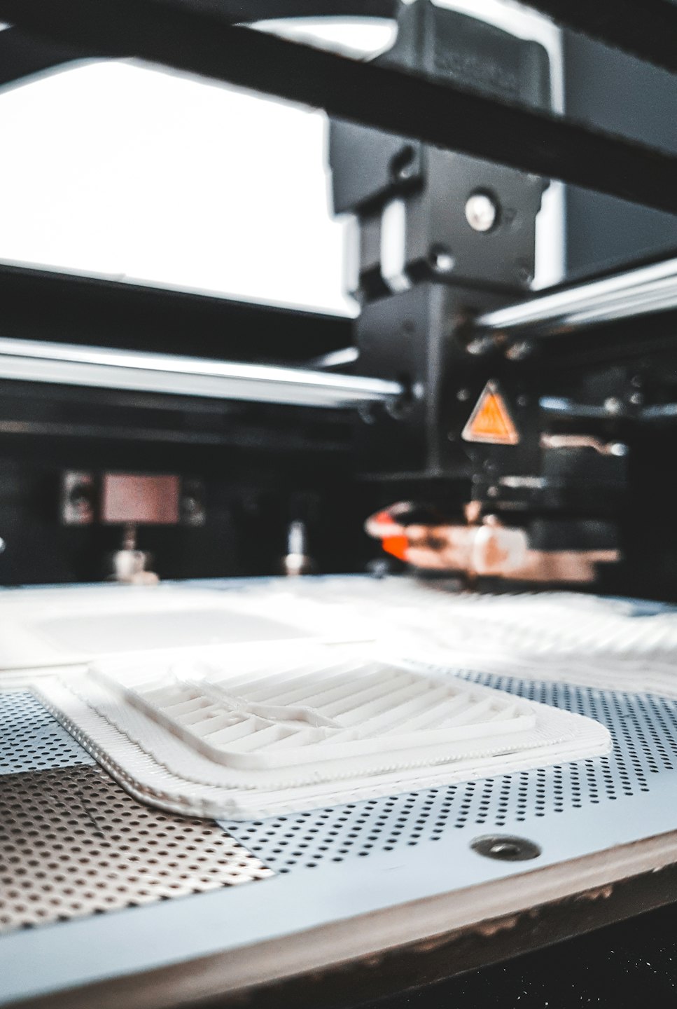 Stampa 3D bianca in fase di fabbricazione su un letto di stampa.