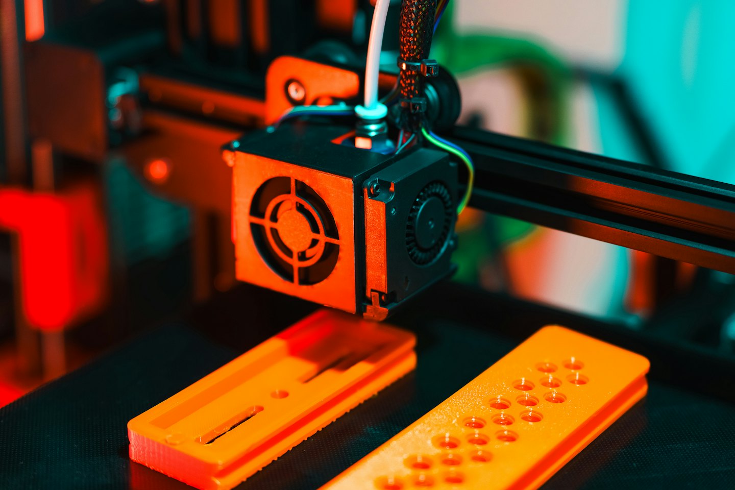 Stampante 3D che estrude filamento arancione su una piastra di costruzione.