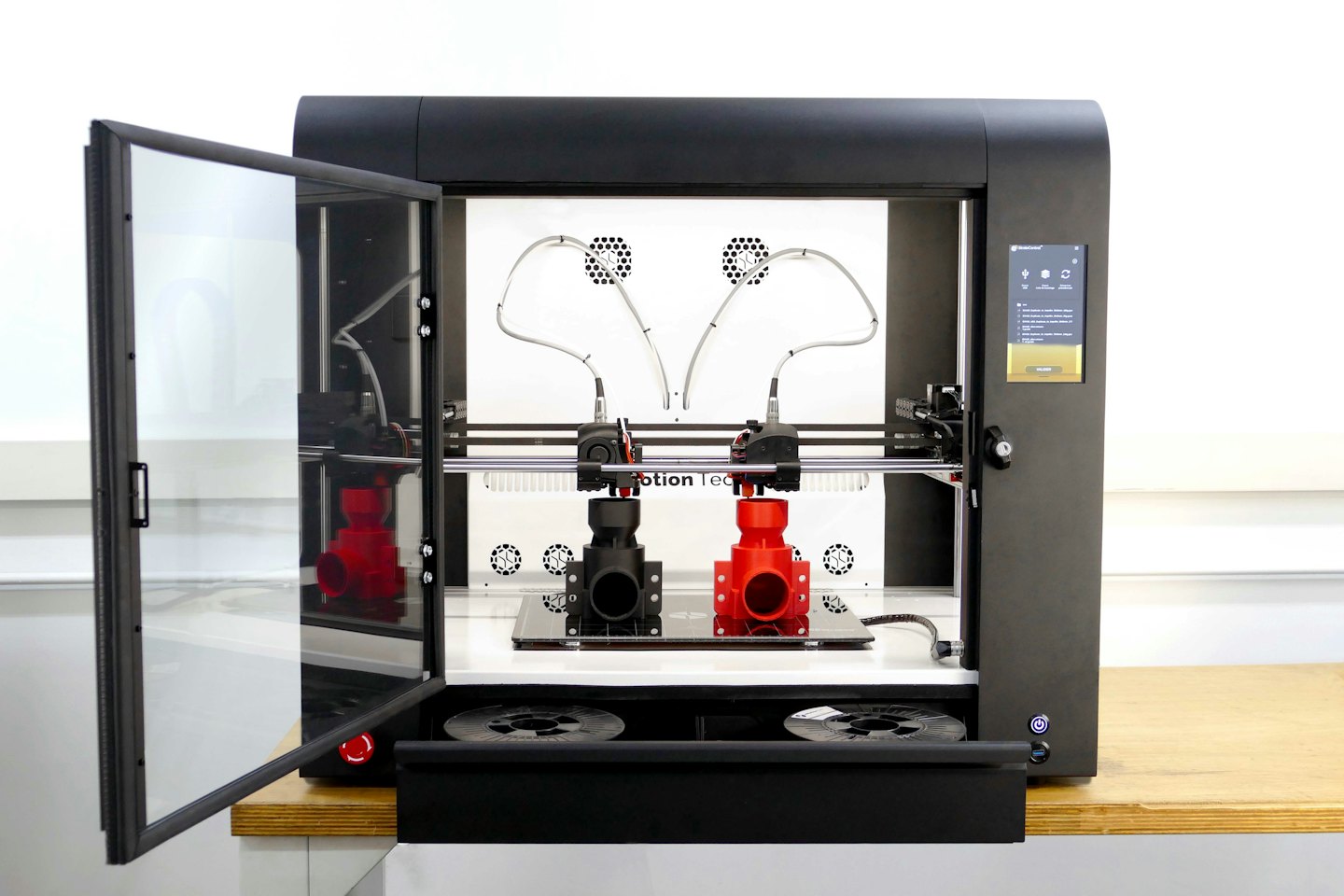 Stampante 3D industriale nera con sportello socchiuso in officina.