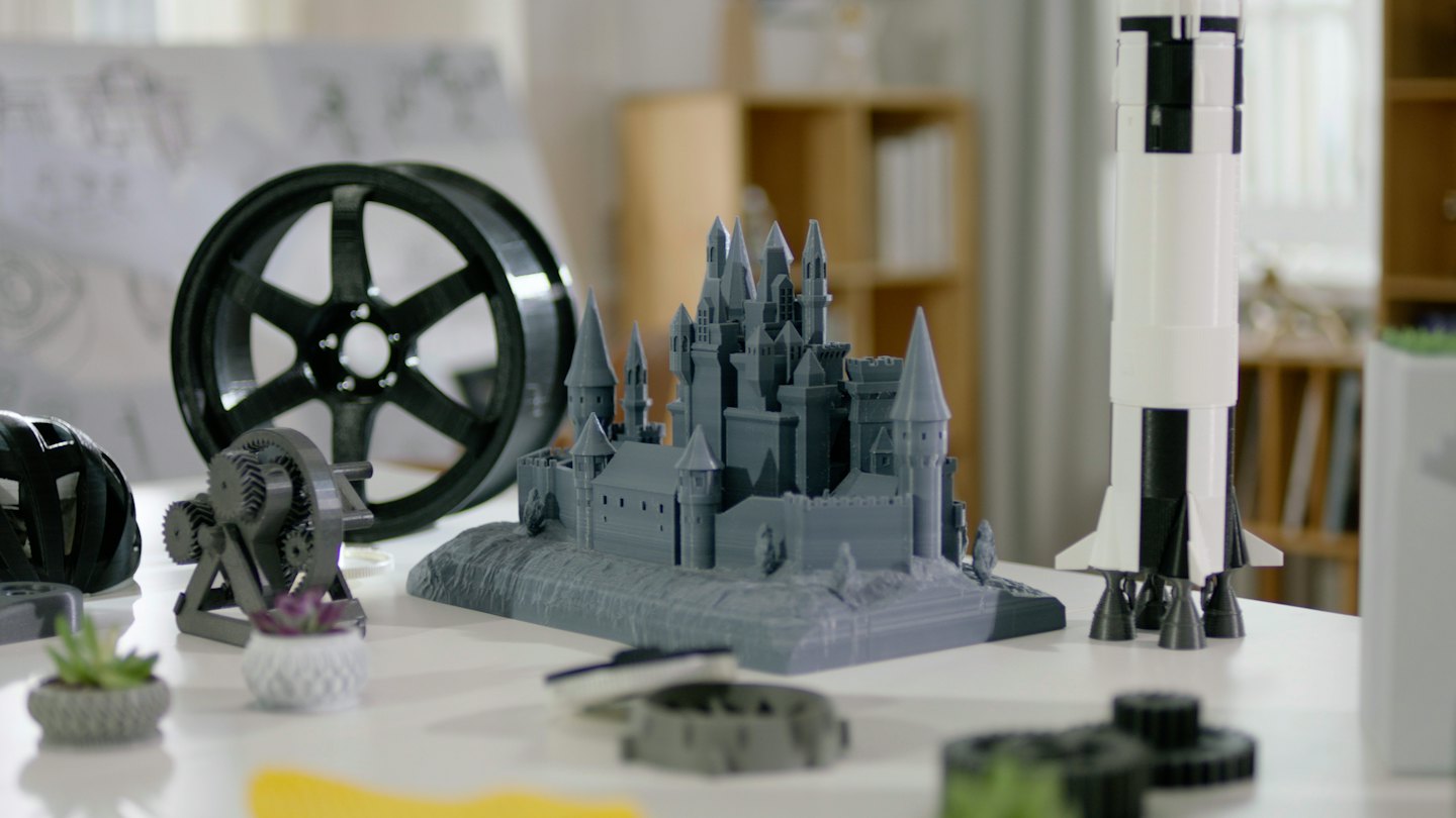Vari oggetti stampati in 3D su un tavolo bianco.