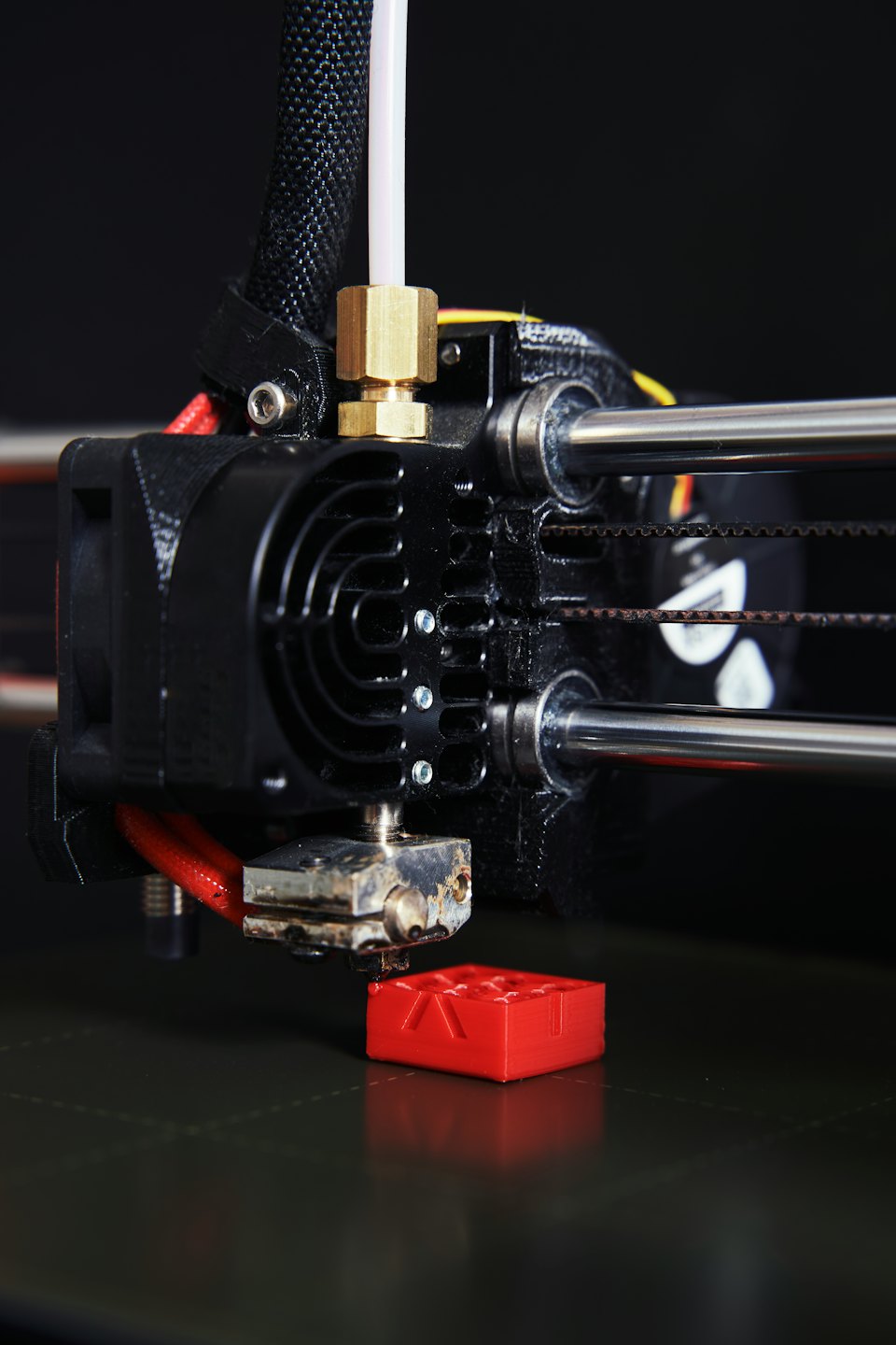 Stampante 3D che estrude filamento rosso sul piano di stampa.