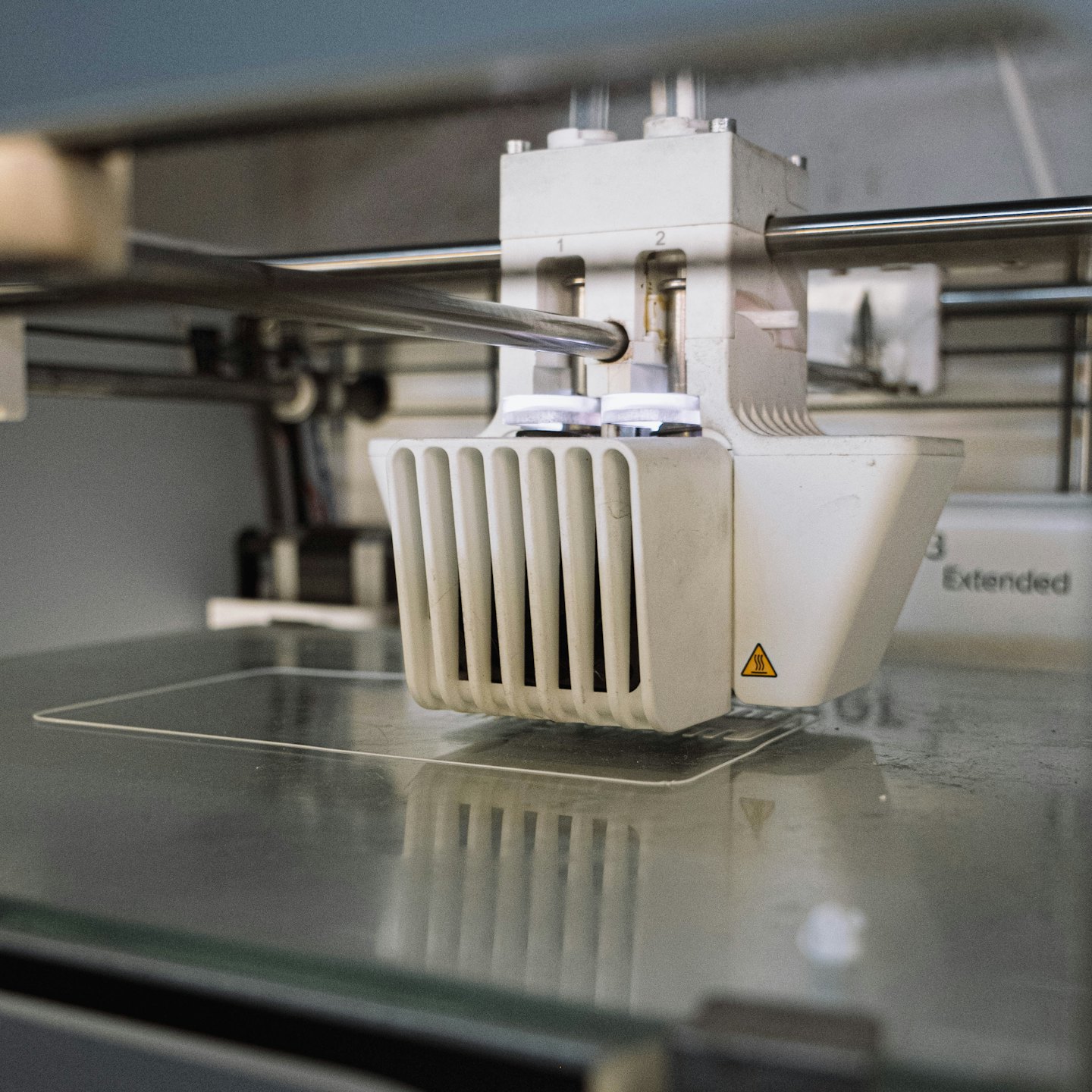 Testina di stampa 3D che deposita filamento trasparente su vetro.
